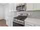 Shows the stainless steel range, microwave, white cabinets, and tile backsplash at 919 Montague Ave, Durham, NC 27703