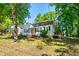 Charming single-story house with a covered porch and black shutters surrounded by mature trees at 1003 E Club Blvd, Durham, NC 27704