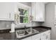 Bright kitchen featuring a stainless steel sink, dark granite countertops, and white cabinets at 1003 E Club Blvd, Durham, NC 27704