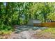 Gravel driveway leading to a storage shed with a natural wood fence, nestled in a wooded area at 1003 E Club Blvd, Durham, NC 27704