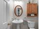 Well-lit bathroom with pedestal sink, wooden framed mirror, and wooden cabinet at 1007 Wellstone Cir, Apex, NC 27502