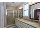 Bathroom featuring double sinks, a shower with glass doors, and decorative mirrors at 1033 Cuthbert Ln, Durham, NC 27703