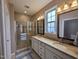 Bathroom with double vanity sinks, granite countertops, tiled floors, walk in shower with seating, and natural light at 1033 Cuthbert Ln, Durham, NC 27703