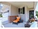 Cozy porch seating area with wicker chairs, an orange chaise lounge, and decor at 1033 Cuthbert Ln, Durham, NC 27703