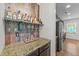 Wet bar in the kitchen with stone counter, glassware, and wood plank accent wall at 108 Yosemite Ct, Holly Springs, NC 27540