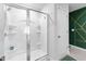 Modern bathroom featuring a glass-enclosed shower with built-in shelves and stylish green accent wall at 1109 Banworth Ct, Mebane, NC 27302