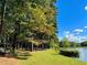 A grassy lakeside with tall trees, offering a peaceful and picturesque waterfront setting at 11813 Edgewater Ct, Raleigh, NC 27614