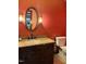 Bathroom featuring warm colored walls, a wood vanity, and an oval mirror at 11813 Edgewater Ct, Raleigh, NC 27614
