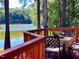 Outdoor deck with a table and seating, overlooking a serene lake at 11813 Edgewater Ct, Raleigh, NC 27614