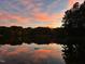 Picturesque lake view featuring a cotton-candy sky at dusk, mirrored on the tranquil water's surface at 11813 Edgewater Ct, Raleigh, NC 27614