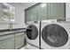 Functional laundry room with modern washer and dryer, plus sink and storage cabinets, all with window light at 1225 Fanning Dr, Wake Forest, NC 27587