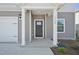 View of a modern front porch with white support beams, a black front door, and a two car garage at 1730 Pie Filling Dr, Haw River, NC 27258