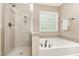 A bright bathroom includes a large tub, walk-in shower, and translucent window for natural light at 196 Norwich Dr, Clayton, NC 27520
