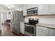 Updated kitchen features white cabinets, stainless appliances, granite counters, and tile backsplash at 215 Rocky Point Ct, Fuquay Varina, NC 27526