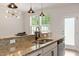 Bright kitchen features a granite countertop, stainless steel sink, and modern lighting fixture above at 2211 Sweet Annie Way, Wake Forest, NC 27587