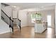 Open-concept living area features wood floors, a staircase, and stylish lighting fixtures over the kitchen island at 2211 Sweet Annie Way, Wake Forest, NC 27587