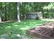 View of backyard and shed in a wooded lot, also showing landscaped flower beds at 2603 Red Pine Rd, Hillsborough, NC 27278