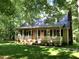 Charming home with a rocking chair front porch surrounded by mature trees and lush lawn at 2603 Red Pine Rd, Hillsborough, NC 27278