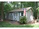 Exterior of grey wooden shed with white trim and American flag in wooded yard at 2603 Red Pine Rd, Hillsborough, NC 27278