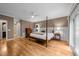 Bedroom featuring hardwood floors, four-poster bed, ceiling fan, and ensuite bathroom at 2616 Dockery Ln, Raleigh, NC 27606