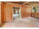 Unfinished living room features wood paneling, exposed ceiling joists, and bright windows at 2670 Nc 210 S, Lillington, NC 27546