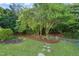 Lush backyard featuring manicured lawn, stepping stones, mature trees, and meticulously arranged mulch beds at 2720 Snowy Meadow Ct, Raleigh, NC 27614