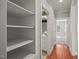 Bright hallway featuring hardwood floors, storage, and a view into the tiled bathroom with a floral wallpaper accent at 2720 Snowy Meadow Ct, Raleigh, NC 27614