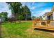 Landscaped backyard featuring green lawn, mature trees, and a wooden deck for outdoor enjoyment at 2910 Reynolda Cir, Durham, NC 27712