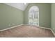 A bedroom with olive-green walls, carpeted floor, and a large arched window that fills the space with natural light at 2917 Kesler Trl, Mebane, NC 27302