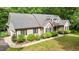 Angled view of tan home with dark shutters, grey roof, and lush green landscape at 2917 Kesler Trl, Mebane, NC 27302