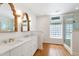 Bright bathroom featuring double vanity, white cabinets, gold fixtures, decorative mirrors, and glass enclosed shower at 3028 Rothgeb Dr, Raleigh, NC 27609