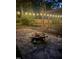 Backyard stone patio with a cozy fire pit and a wooden swing, illuminated by string lights at 305 Monterey Ct, Benson, NC 27504