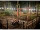 Backyard stone patio with fire pit, wooden swing, and festive string lights at dusk at 305 Monterey Ct, Benson, NC 27504