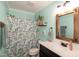 The bathroom features a floral shower curtain, white vanity with black hardware, and light teal walls at 305 Monterey Ct, Benson, NC 27504