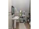 Compact bathroom with pedestal sink, vanity mirror, and storage shelving at 305 Monterey Ct, Benson, NC 27504