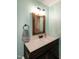 This bathroom features a dark wooden vanity with a white countertop, rustic mirror, and light teal walls at 305 Monterey Ct, Benson, NC 27504