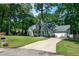 Inviting home with a spacious driveway, attached garage, and a lush green lawn surrounded by mature trees at 305 Monterey Ct, Benson, NC 27504
