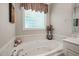 This bathroom features a large soaking tub, tiled floors, and a decorative window for natural light at 3201 Keighley Forest Dr, Wake Forest, NC 27587