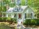 Charming home featuring a welcoming red door, stone chimney, and lush green landscaping at 3201 Keighley Forest Dr, Wake Forest, NC 27587