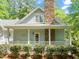 Charming home featuring a stone chimney, covered porch with a white railing, and lush landscaping at 3201 Keighley Forest Dr, Wake Forest, NC 27587