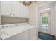 Laundry room with white washer and dryer, storage cabinets, and access to the exterior at 3201 Keighley Forest Dr, Wake Forest, NC 27587
