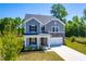 Inviting two-story home featuring gray siding, stone accents, a manicured lawn, and a welcoming front porch at 325 Porterfield Dr, Youngsville, NC 27596