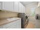 Functional laundry room with ample storage, a utility sink, and modern washer/dryer at 39 Forked Pine Ct, Chapel Hill, NC 27517