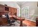 An office with a wooden desk, wooden built-in cabinets, and a comfortable black chair near a window at 39 Forked Pine Ct, Chapel Hill, NC 27517