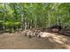 Outdoor fire pit surrounded by natural seating amidst a lush, green forest landscape at 4022 Tecolote Way, Hillsborough, NC 27278