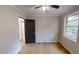 Cozy bedroom features hardwood flooring, a ceiling fan, a window and a black door at 4501 Rockwood Dr, Raleigh, NC 27612