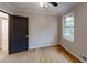 Cozy bedroom features hardwood flooring, a ceiling fan, a window and a black door at 4501 Rockwood Dr, Raleigh, NC 27612