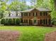 Beautiful brick home with lush green lawn, mature trees, and manicured shrubs, offering a welcoming and serene atmosphere at 4505 Wood Valley Dr, Raleigh, NC 27613