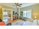 Bright bedroom featuring hardwood floors, a ceiling fan, a large window, and multiple doorways leading to other spaces at 457 S Greensboro St, Carrboro, NC 27510