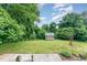 Lush backyard with a well-maintained lawn and a charming storage shed surrounded by mature trees and garden at 4832 Brookhaven Dr, Raleigh, NC 27612